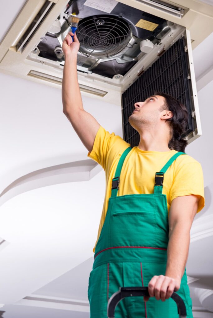 Aircon technician servicing a ceiling-mounted air conditioning unit