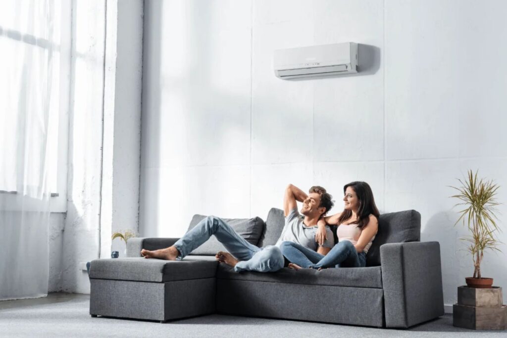 Couple relaxing comfortably in a living room with a wall-mounted air conditioner